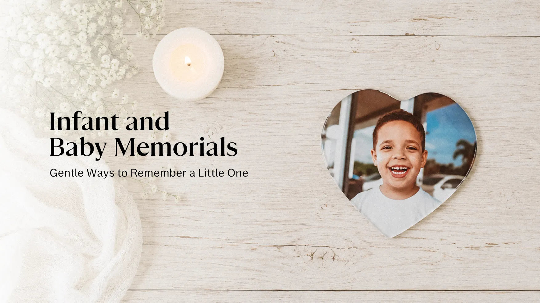 A gentle memorial display for a baby featuring a small personalised porcelain plaque, a white candle, and soft white flowers on a pale wooden surface